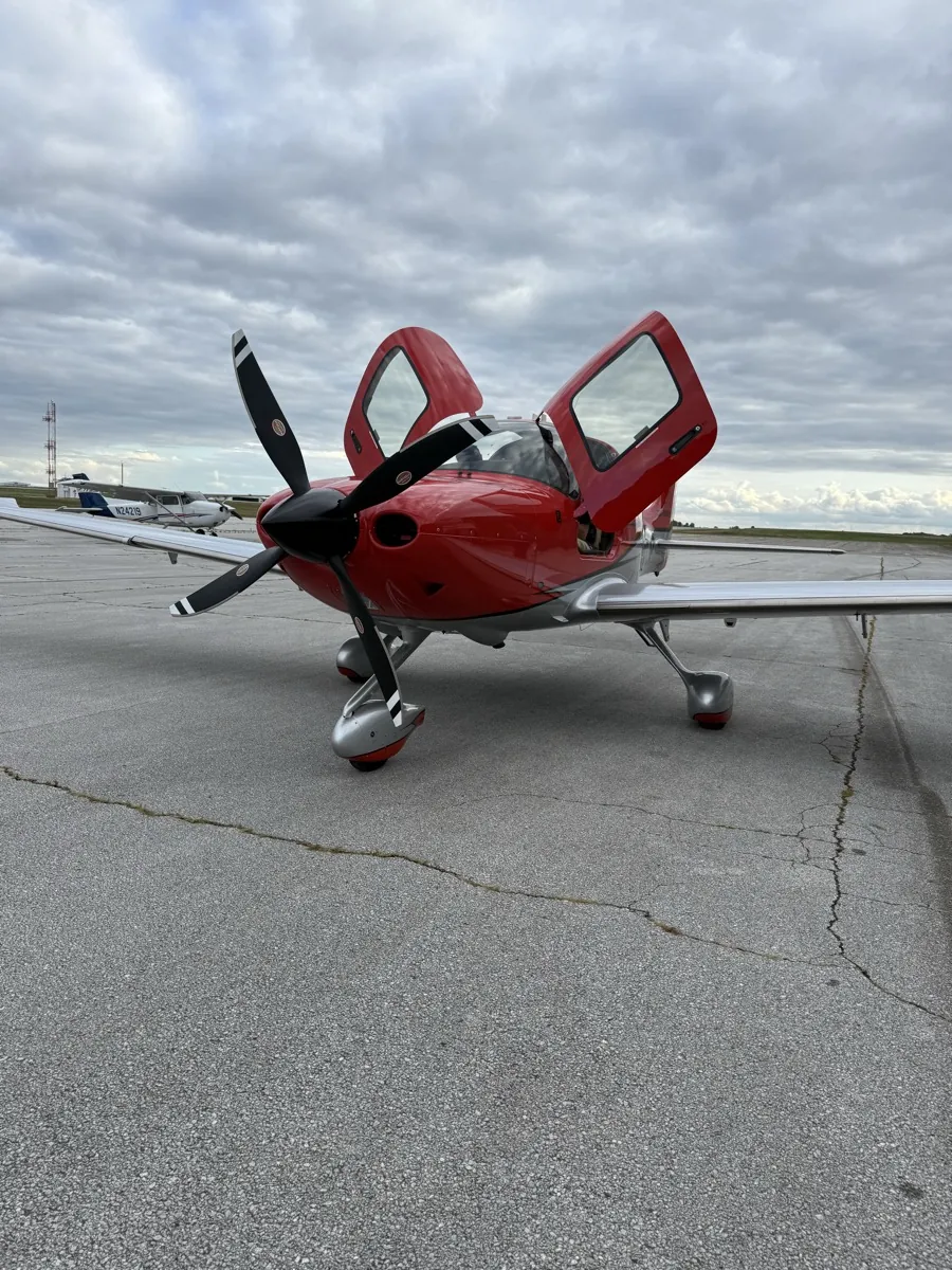 Red Cirrus aircraft with the doors open on the ramp