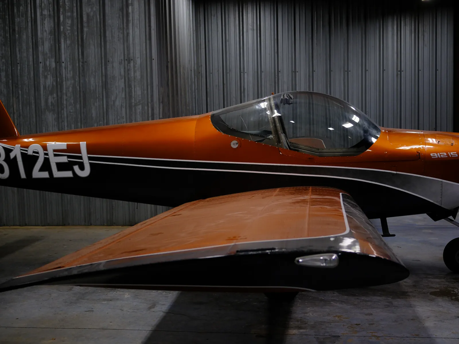Side view of N812EJ, the orange RV-12iS, showing its tail number and bubble canopy