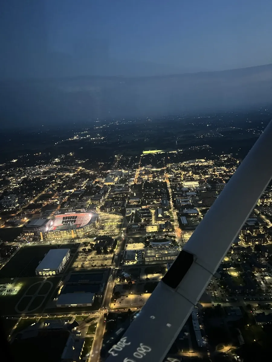 City lights at night seen from the cockpit over the wing strut